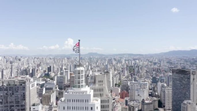 圣保罗州旗飘扬在建筑物的顶部，城市在背景中，蓝天