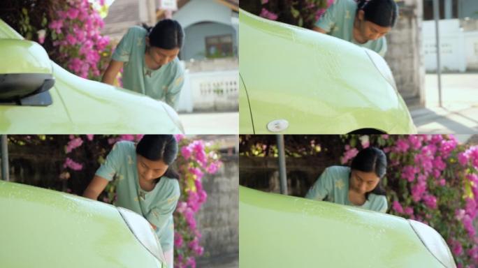 亚洲女孩在家洗绿色汽车和挡风玻璃，生活方式概念。