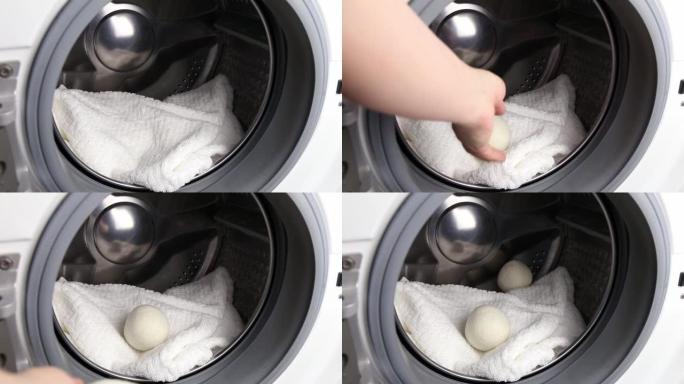 女人在洗衣机概念中使用羊毛烘干机球做更柔软的衣服，同时滚筒烘干。放电静电，缩短干燥时间，节约能源。