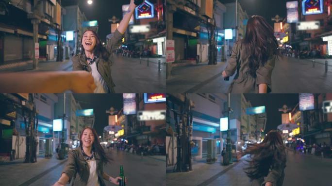 亚洲女性旅行者的肖像握着男朋友的手，走在街上。在城市旅行的年轻男女游客一起度过假期，并在漆黑的夜晚在