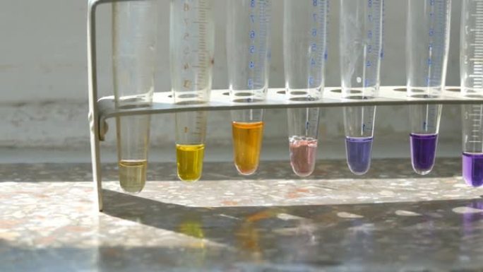 在带有大理石窗台的旧窗户上的实验室中，医用试管中的彩色液态水。