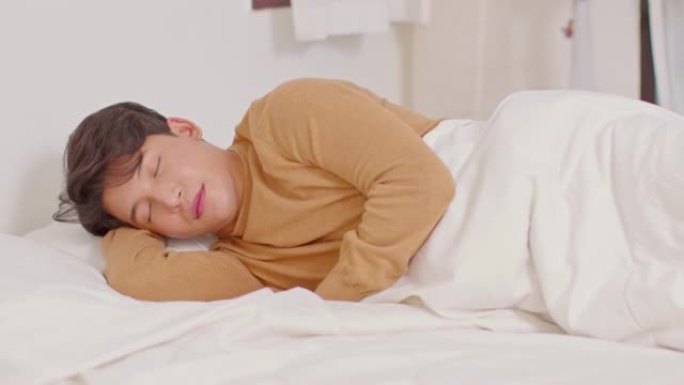 英俊迷人的亚洲男人早上躺在舒适的卧室的床上睡觉和甜蜜的梦，感觉如此放松和舒适。健康的年轻男性在家睡觉