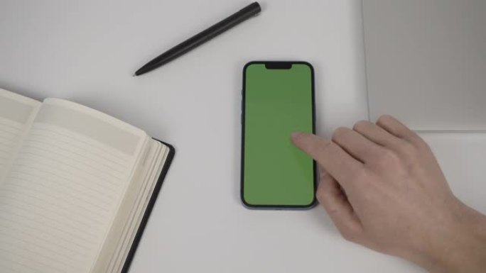男人的手的特写镜头在办公室使用带有水平绿屏的智能手机