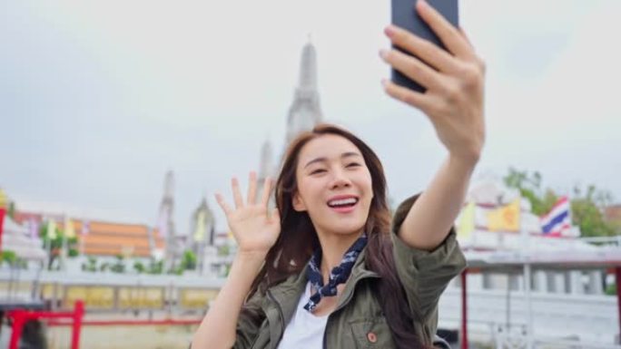 亚洲女性背包客使用相机自拍并在城市拍照。年轻女孩旅游旅行者独自在街上旅行，在泰国佛寺度假旅行时使用手