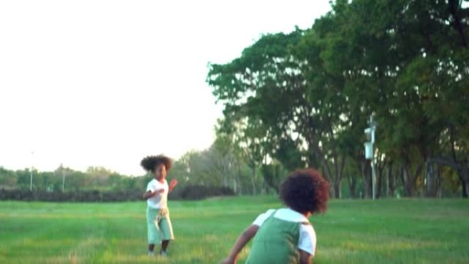 阳光明媚的日子，欢快的小非洲裔美国人四，五岁的双胞胎男孩和女孩在公园里一起踢足球。所有球员传球时都很