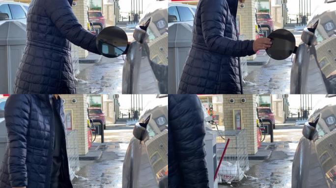 冬季，一个人关闭汽车上油箱加油口颈的车门弹簧外壳口袋。概念: 汽油价格。