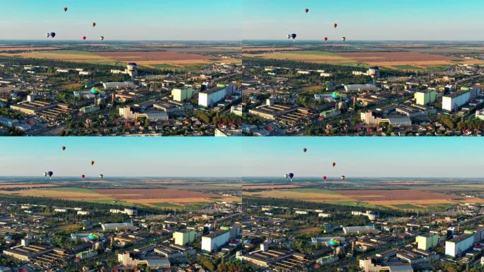 五彩气球飞过田野、房屋、树木。蓝天。美丽的夏季飞行在城市上空。