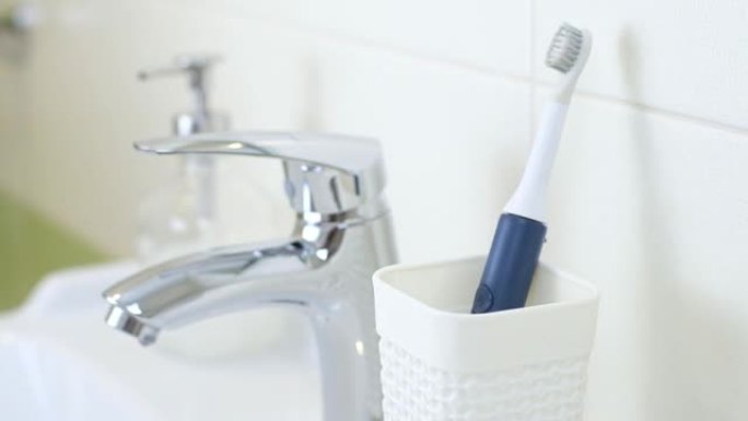 女人在家里的浴室里使用新型现代超声波牙刷。口腔卫生，牙齿和牙龈健康，健康牙齿。牙科产品超声波振动牙刷