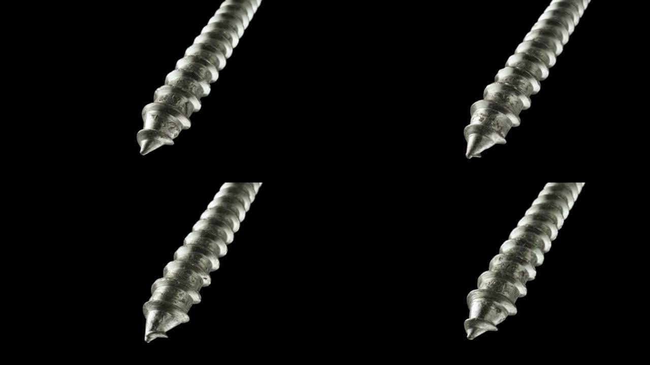 在孤立的黑色背景上旋转的钢螺丝或金属螺栓的详细照片。螺旋线程超级宏特写。修理或施工用紧固工具。慢动作