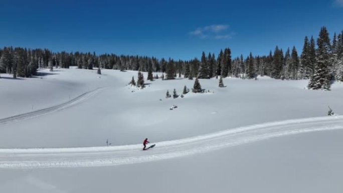 在科罗拉多州大梅萨国家森林的一条经过修饰的小径上，越野滑雪者滑雪和练习 “斜跨步” 方法的广角航拍