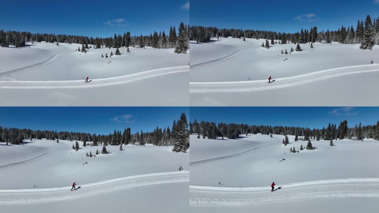 在科罗拉多州大梅萨国家森林的一条经过修饰的小径上，越野滑雪者滑雪和练习 “斜跨步” 方法的广角航拍