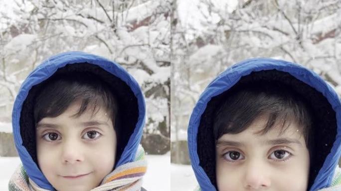 穿着蓝色冬装的有趣小男孩在降雪时行走。孩子们的户外冬季活动。