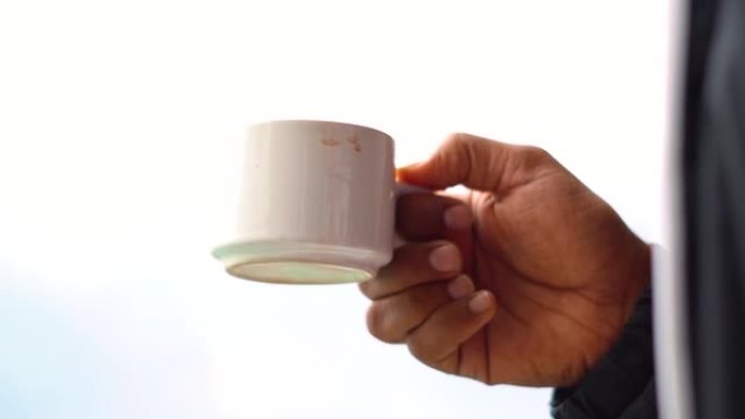 一个印度男子拿着茶杯的特写镜头。早上端着一杯茶的人。咖啡因和茶成瘾概念。成年男子清晨喝茶。