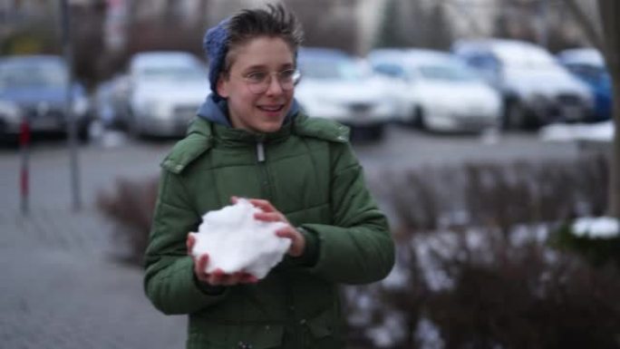 一个十几岁的男孩在冬天扔雪球的肖像