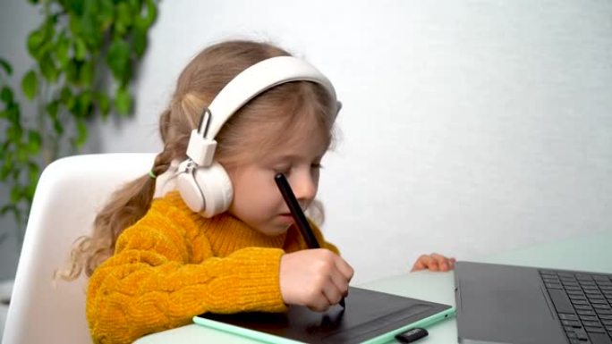 一个小女孩用图形平板电脑在线学习，一个戴着耳机的孩子在笔记本电脑上学习图形设计