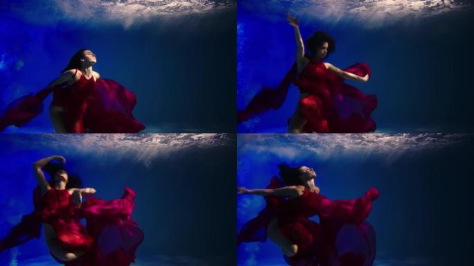 一个年轻女子在水下游泳的神奇水下镜头。红色连衣裙