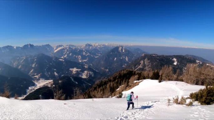 活跃的女人，背着背包，在弗赖贝格的山峰上，可以欣赏到奥地利卡林西亚卡拉万克斯的白雪皑皑的山峰。泽尔·