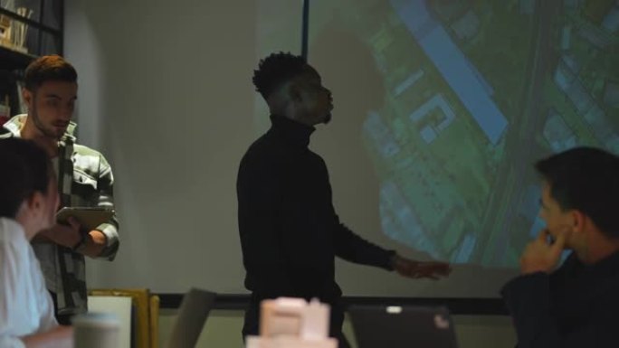 非洲男子向员工同事展示项目。自信的时尚男人站在会议室。具有元数据和数字实时交互屏幕新技术的概念业务。