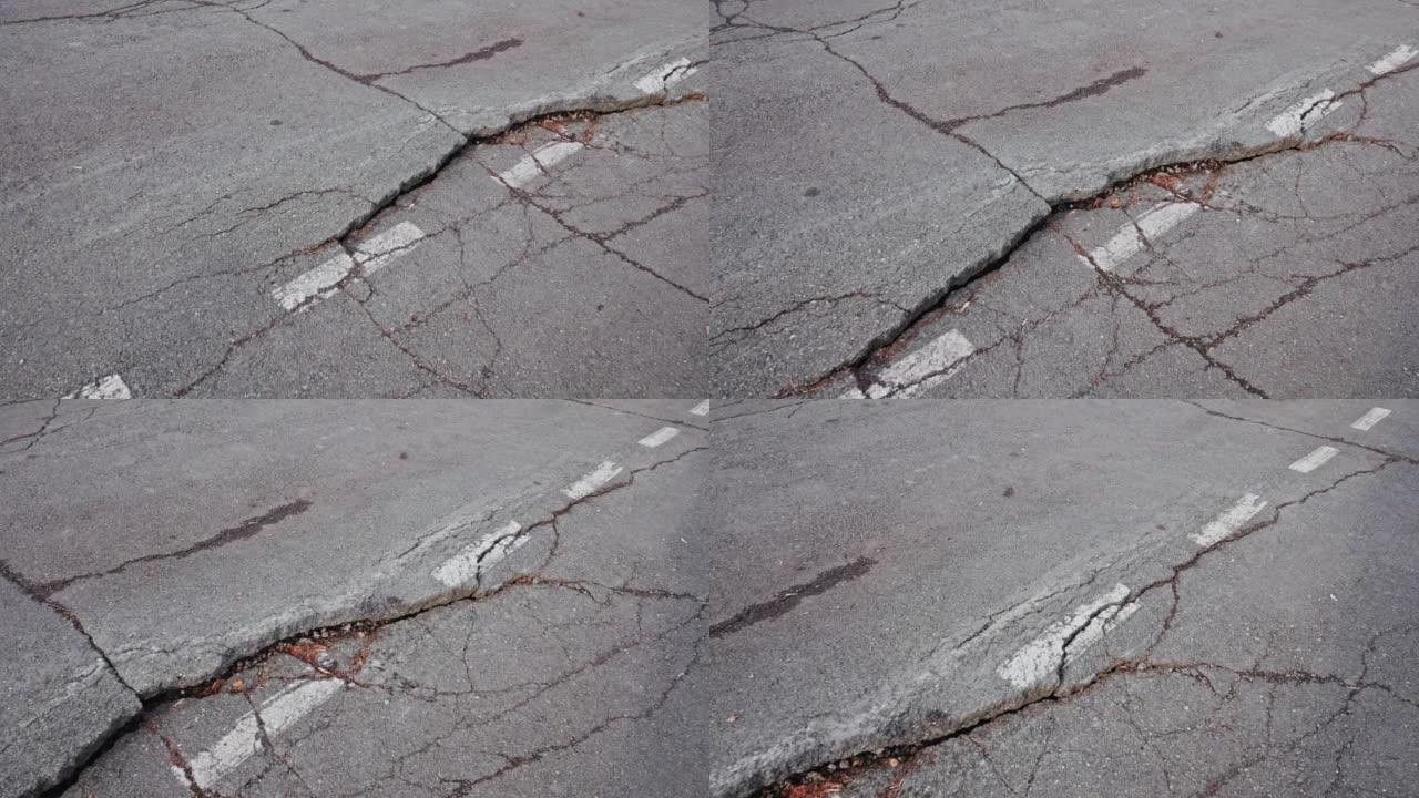 白色道路标记旁的道路上有深层断层的裂缝