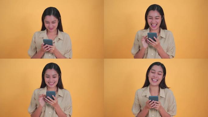 年轻美丽的亚洲女性20多岁，在孤立的工作室黄色背景下使用移动智能手机。面部表情，惊讶于激动人心的微笑