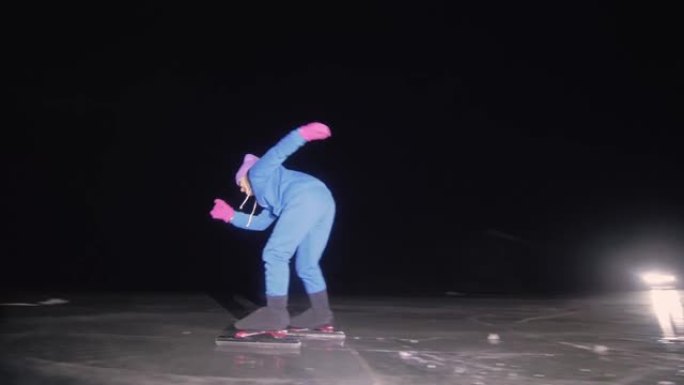 孩子在冰上速滑训练。夜间滑冰。这个女孩在冬天穿着运动服和运动眼镜滑冰。户外慢动作