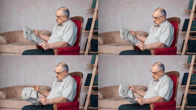 专注的老人在家里的老式扶手椅上学习有趣的报纸媒体出版物