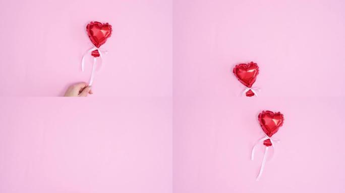 红心气球飞，手抓住它在柔和的粉红色主题。停止运动平铺