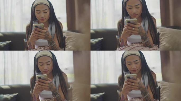 年轻亚洲女性在家中使用智能手机的肖像。