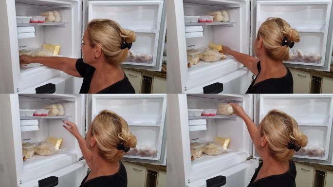 家庭主妇在冰箱里寻找冷冻面包
