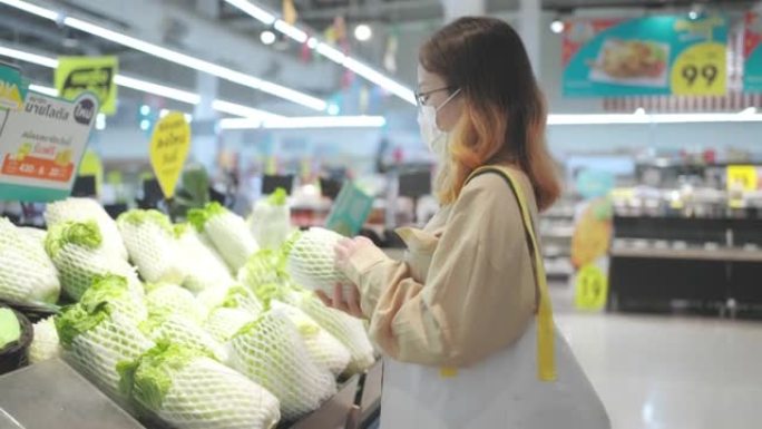 年轻女子金色长发，戴眼镜，戴口罩，在商店用布袋购物。有意识的消费者，全球变暖，不使用塑料，可持续的概