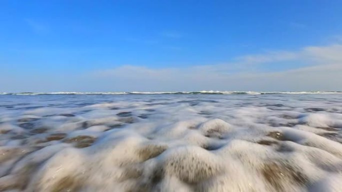在海滩上飞溅波浪。海浪溅起相机。从低角度拍摄动作相机。