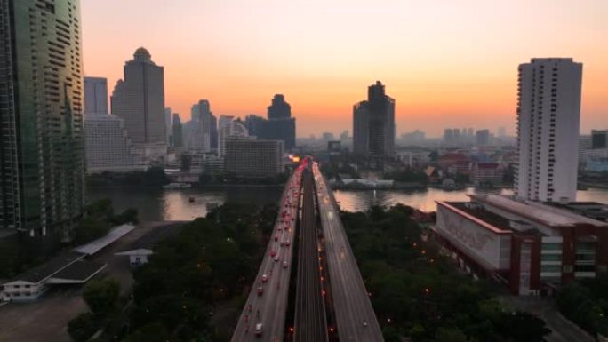 空中无人机在曼谷的超披亚河上的高速公路和地铁天空列车上的交通车灯的日出场景