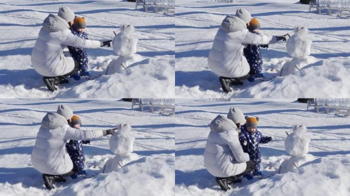 孩子在雪地里迈出了第一步，和妈妈一起散步。1岁的男婴在冬天学习与妈妈在公园散步。