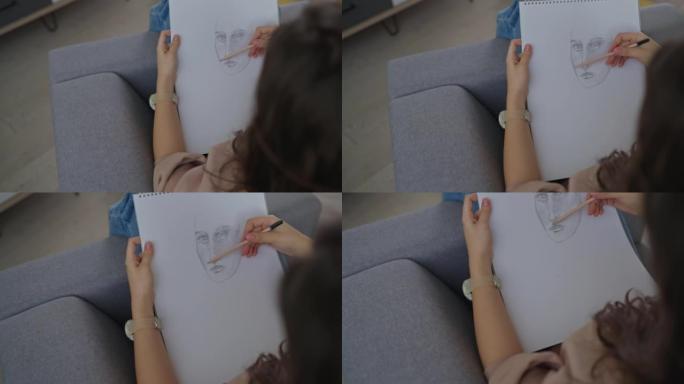 无法辨认的高加索少女在她的素描本中绘画