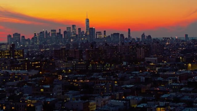 曼哈顿市区和自由塔上空的戏剧性天空在夜晚照亮。日落时分，可以看到布鲁克林住宅区的远景。轨道平移摄像机