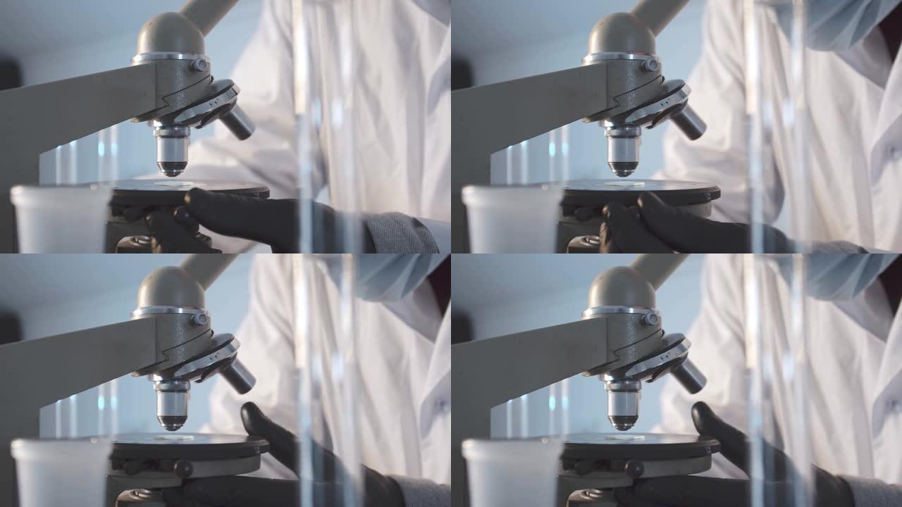 一个男人在实验室里的特写镜头在载玻片上安装了一个显微镜。在科学实验室进行研究工作。戴着防护橡胶手套的