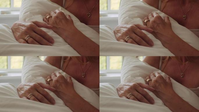 手指上有戒指的女人，心脏项链在床上抓着枕头