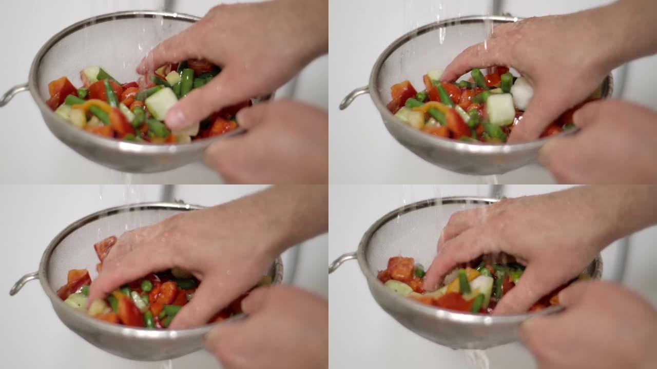 雄性手洗黄瓜辣椒粉番茄青豆玉米番茄辣椒花椰菜胡萝卜。用手慢动作用水清洗新鲜切碎的蔬菜。素食有机保健食