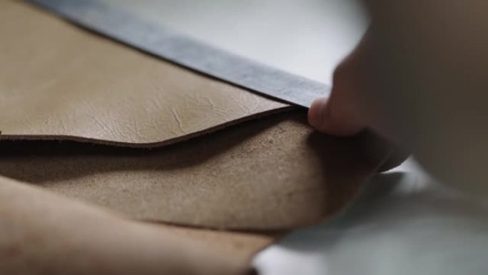 艺术家的手用尺子测量皮革作品。