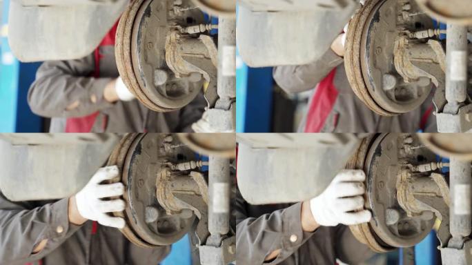 一名戴着白手套的工人从汽车制动系统上卸下了一个生锈的旧制动鼓