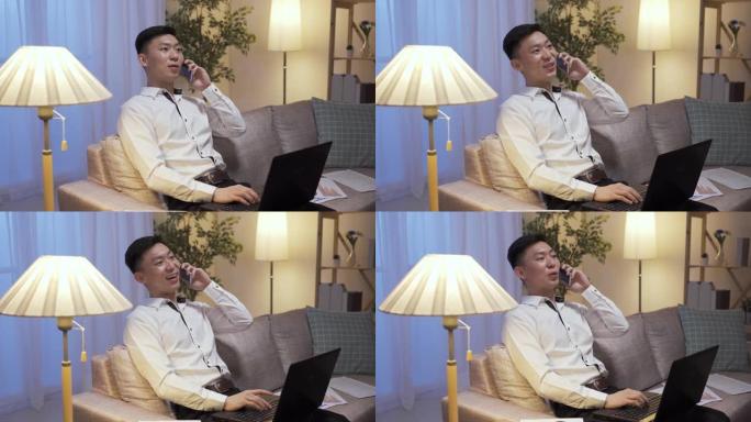 成功的亚洲男性企业家在休假期间在家客厅闲暇时在电话上轻敲笔记本电脑键盘