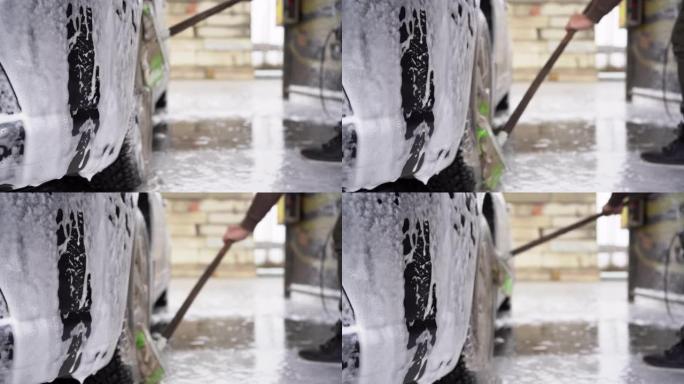 一名男性司机在自助洗车场洗车的特写镜头。用特殊的刷子清洁光盘。复制空间。