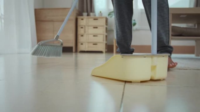 女人用扫帚清洁和扫除地板上的灰尘
