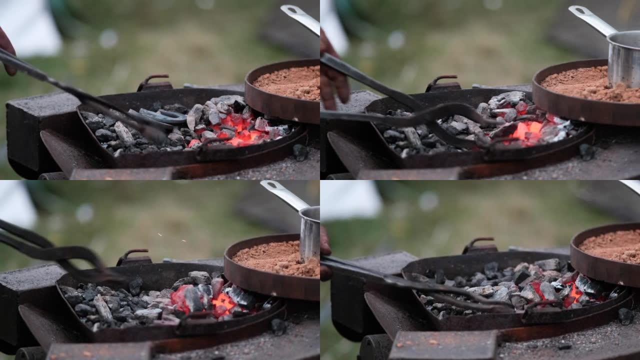 特写铁匠用钳子将熔融的红色金属马蹄铁在火上。锻造工艺。