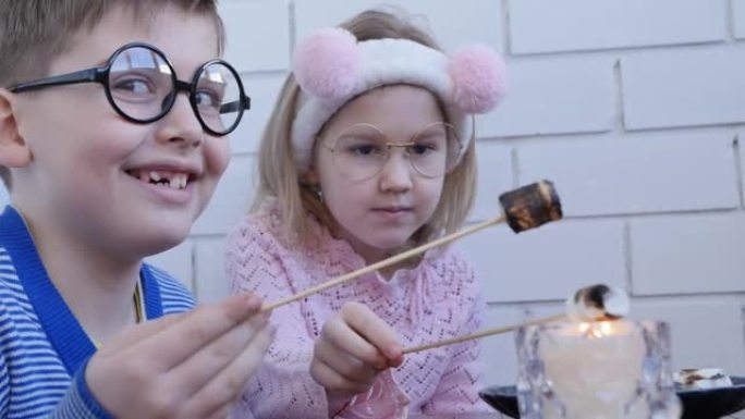 孩子们在烛火上用棍子炸棉花糖。