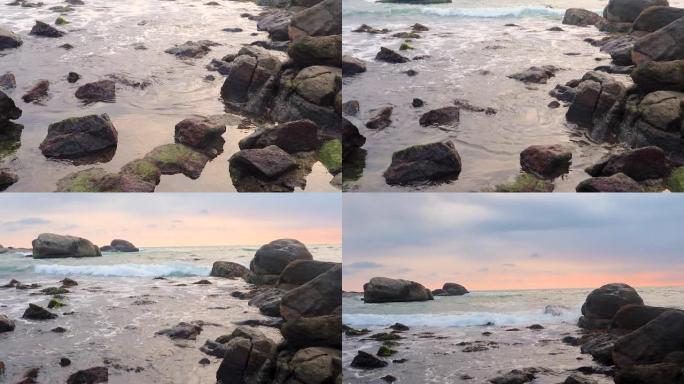 傍晚时分，带有海浪的小石头通向日落，五颜六色的戏剧性天空地平线