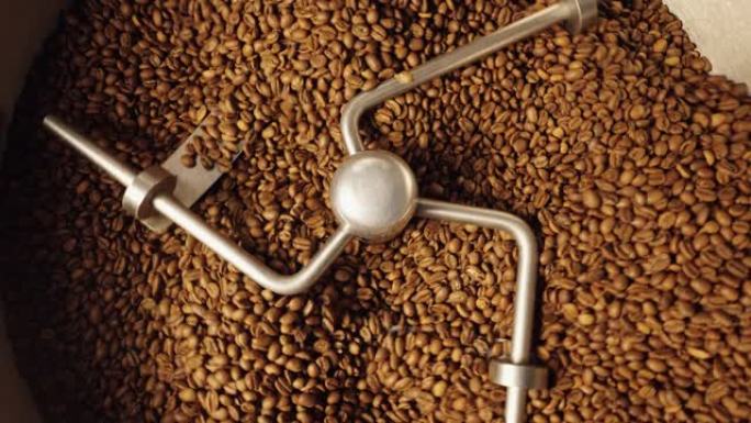 工业混合机的俯视图在焙烧炉中混合烘焙咖啡豆，特写。工厂咖啡焙烧机的焙烧过程。咖啡馆的餐饮背景。慢动作
