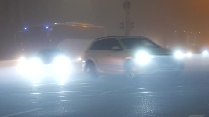 法国斯特拉斯堡-2021年11月6日: 有雾的秋季傍晚城市，沿街行驶的汽车，大灯和雾灯亮起