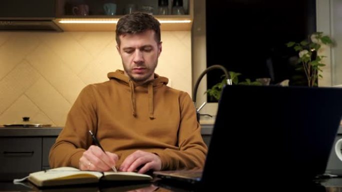 男子在家庭工作场所使用笔记本电脑，阅读纸质文件