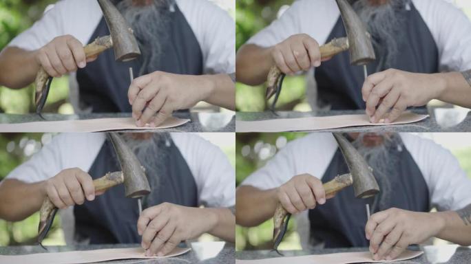 工匠的手用锤子在皮革上制作图案。